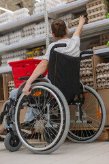 Naklejka premium A Caucasian woman in a wheelchair shopping in a supermarket.