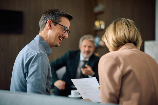 Happy couple analyzing paperwork during meeting with financial counselor in office.