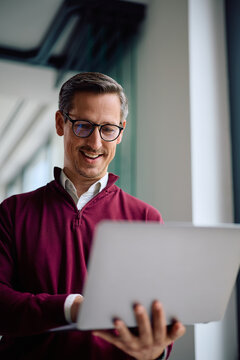 Happy entrepreneur using laptop while working in office.