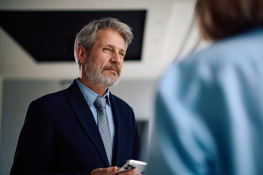 Mature businessman communicating with colleague in office.