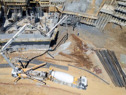 Aerial view of a concrete pump truck operating at a large construction site with deep excavation, steel reinforcement bars, and concrete foundations in Istanbul, Istanbul, Turkiye.