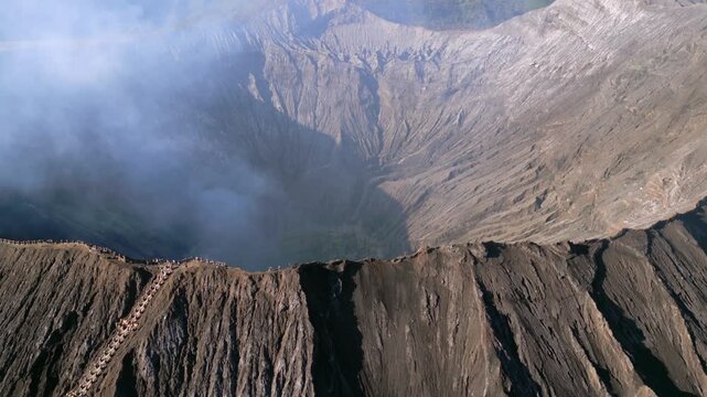 Aerial view of Mount Bromo crater in East Java, Indonesia, with volcanic steam rising from the caldera. Dramatic volcanic landscape showcasing geothermal activity and the raw power of nature.