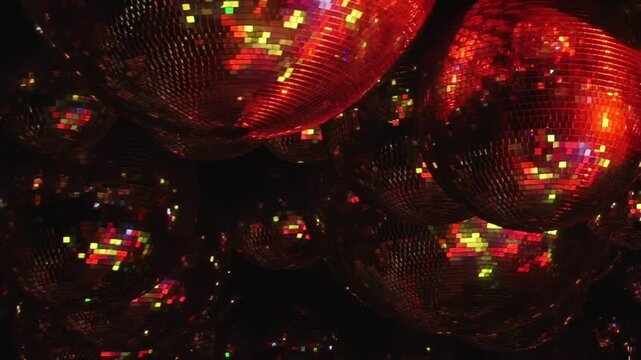 Dazzling array of mirrored spheres reflects brilliant red, green, and purple light. Glittering surfaces create enchanting, dynamic display, perfect for lively club or festive evening atmosphere.
