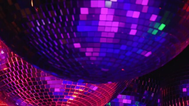 Multiple shimmering disco balls reflect an evolving cascade of vibrant lights.
