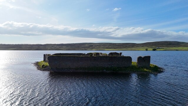 Lochindorb Castle, a 13th-century medieval stronghold in the Scottish Highlands, is captured from a side angle at a 45-degree perspective, showing its ruined stone structure rising from an island 