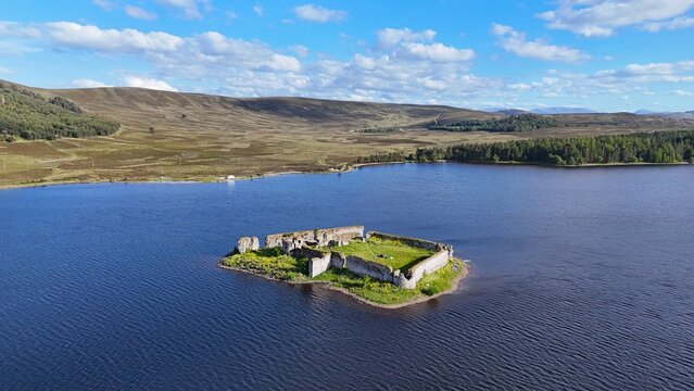 Lochindorb Castle, a 13th-century fortress in the Scottish Highlands, stands on a small island, viewed from above amid dark waters and moorland.