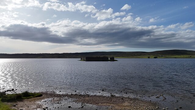 Lochindorb Castle in Scotland, scottish highland  appears from a very far side view, a tiny 13th-century island ruin surrounded by vast Lochindorb and Highland wilderness.