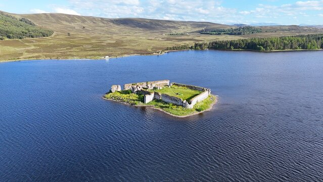 Lochindorb Castle, built in the 13th century, stands on an island in the Scottish Highlands. Aerial view reveals medieval ruins surrounded by moorland.