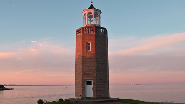 Groton, Connecticut, USA - Avery Point Lighthouse With Sailboat And Cargo Vessel On Long Island Sound