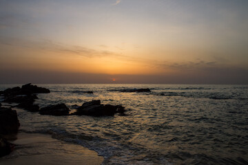 Obraz premium Stunning sunset view over calm ocean waters with rocky shoreline