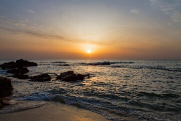 Fototapeta premium Serene sunrise over the ocean with rocky coastline and gentle waves