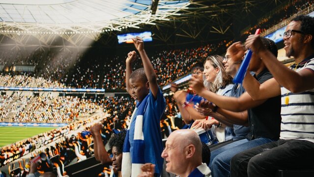 Young soccer fan standing among cheering supporters during live football match, capturing excitement of childhood and sports family, Black father acting as role model during fun football match.