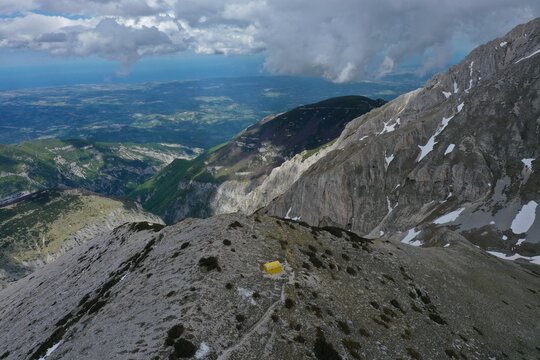 Aerial view of Bivouac Carlo Fusco on a rocky mountain ridge with snow patches, overlooking the rugged peaks of the Majella National Park, Pennapiedimonte, Abruzzo, Italy.