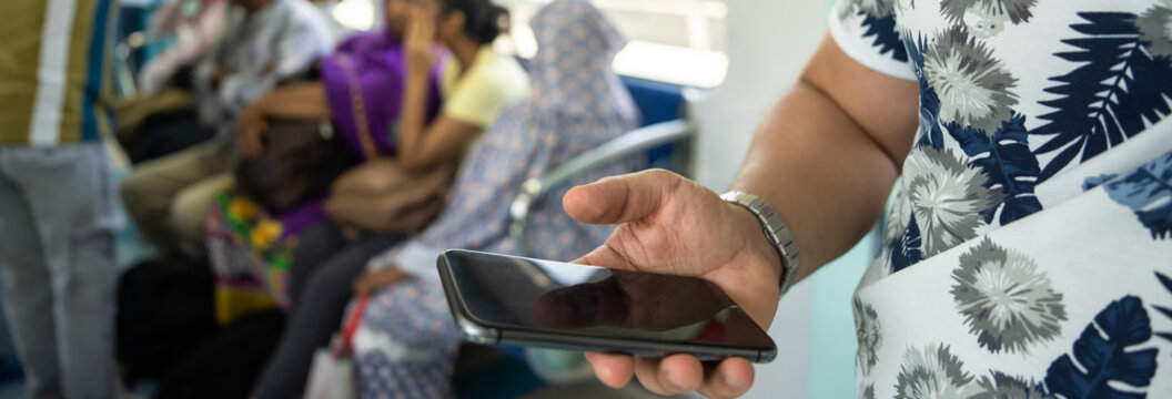 Man standing inside metro train while using smartphone, crowded urban commuting scene, public transportation, digital lifestyle, city travel, and modern mobility concept.