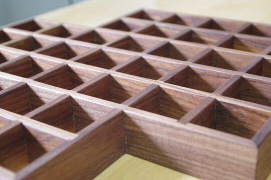 Close-up view of a handcrafted wooden organizer featuring multiple square compartments and rich natural wood grain.