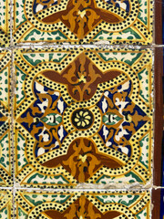 Obraz premium A detailed close-up of a decorative, vintage Portuguese azulejo tile featuring complex, colorful geometric and floral motifs in shades of brown, yellow, green, and deep blue, showcasing exquisite craf