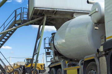 Naklejka premium Modern concrete manufacturing process with industrial mixer vehicle under batching plant station building materials production logistics concept
