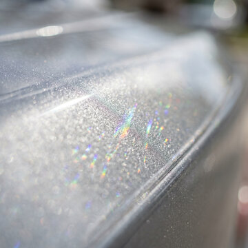 Sparkling silver car paint with rainbow light reflections, close-up detail