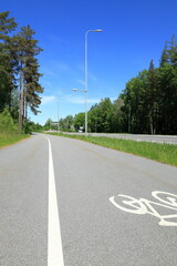 Fototapeta premium Swedish road during the summer. Green nature and pleasant weather. Stockholm, Sweden. For walking or driving a bike.