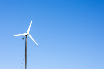 Small wind turbine against blue sky with copy space © Anastasiia