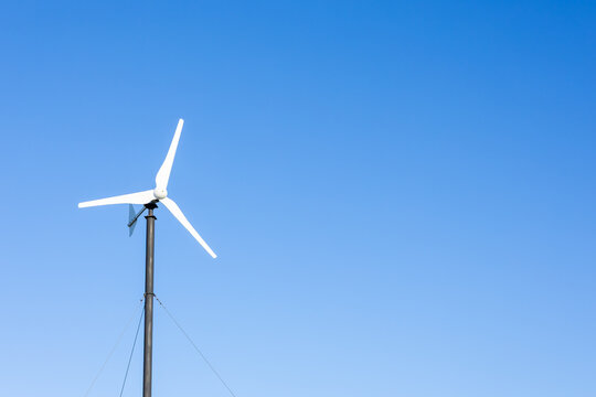 Small wind turbine against blue sky with copy space