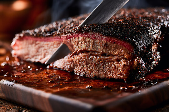 Macro close up of slicing smoked beef brisket flat on a wooden cutting board