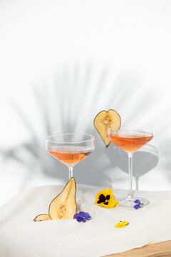 Two rose wine glasses with summer cocktails and dried fruit appetizers
