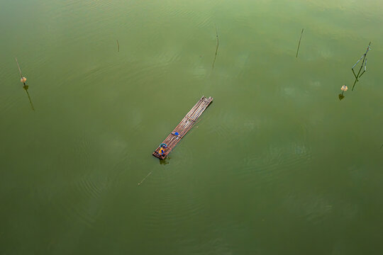 Aerial view of a fisherman on a bamboo raft in the green waters of Rowo Jombor, Bayat, Central Java, Indonesia.