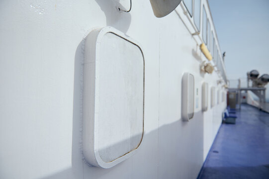 White ferry deck with portholes and hatches on a blue ship exterior