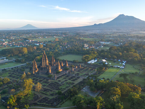 Aerial view of Prambanan Temple surrounded by lush gardens and ancient stone ruins with distant mountains in Kecamatan Prambanan, Daerah Istimewa Yogya, Indonesia.