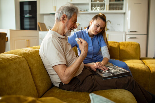 Caregiver comforting senior man with photo album at home