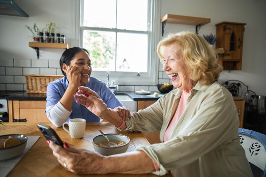 Caregiver and senior laughing over breakfast at home