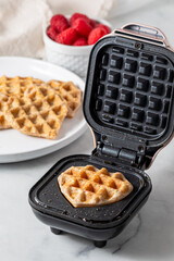 Naklejka premium A freshly made heart shaped mini waffle on a mini waffle maker. 