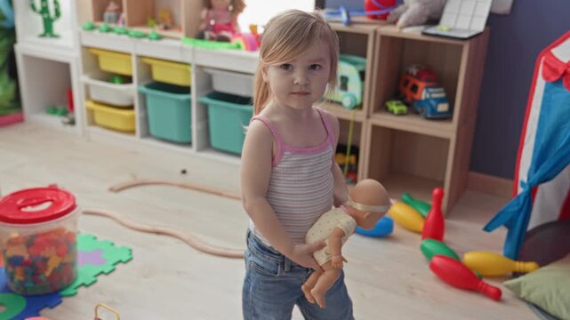 Girl holding doll by arm beside striped play tent inside a children's playroom building; playful childhood.