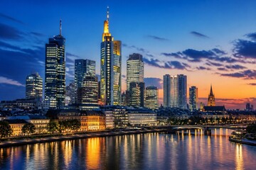 Naklejka premium City skyline illuminated at dusk along riverside waterfront