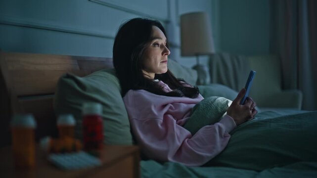 Upset lady watching mobile phone looking medicine bottles at evening closeup