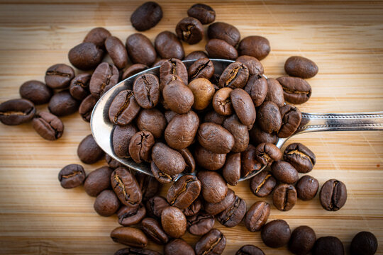 coffee beans on teaspoon with a wooden background