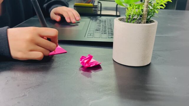 Note-taking at work desk, 16:9 widescreen footage, writing on pink sticky notes, productive workspace, office environment, planning and brainstorming, creative workflow, desk setup.