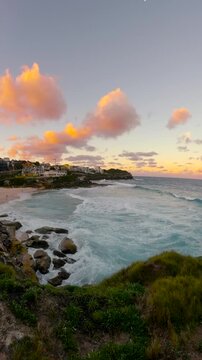Slow motion fisheye video of Tamarama Beach viewed from a coastal lookout at sunset, with calm ocean water, soft golden light, and the Sydney coastline, Australia.
