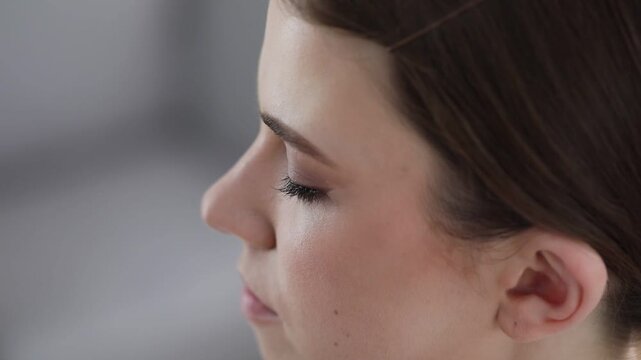Makeup artist applying false eyelashes on woman's face indoors, closeup