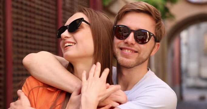Lovely couple in sunglasses on city street, camera moving right