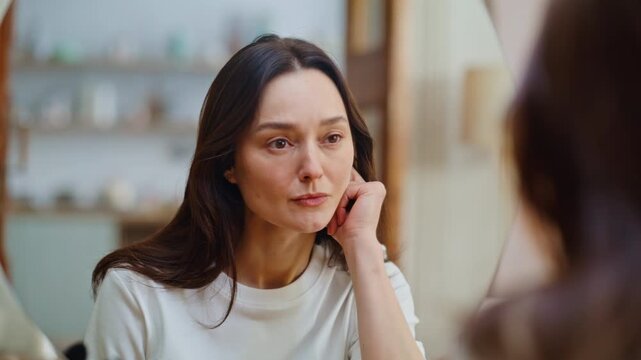 Sad woman looking mirror thoughtfully at quiet home setting closeup. Upset lady