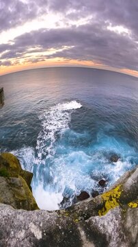 Slow motion fisheye video of Bondi Beach viewed from a coastal lookout at sunset, with calm ocean water, soft golden light, and the Sydney coastline, Australia.