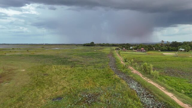 Aerial view of a dramatic storm and heavy rain falling over a rural landscape in Thailand.