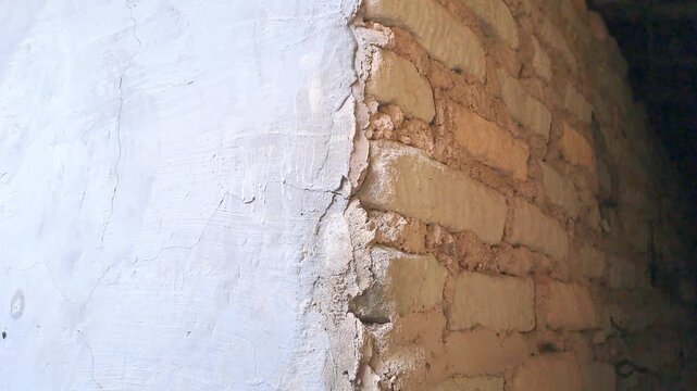 Cracked exterior house wall with mold, grass, and exposed white brick. Damaged plaster texture outdoor. Building deterioration stock video 4K for inspection, construction, repair, maintenance, real es
