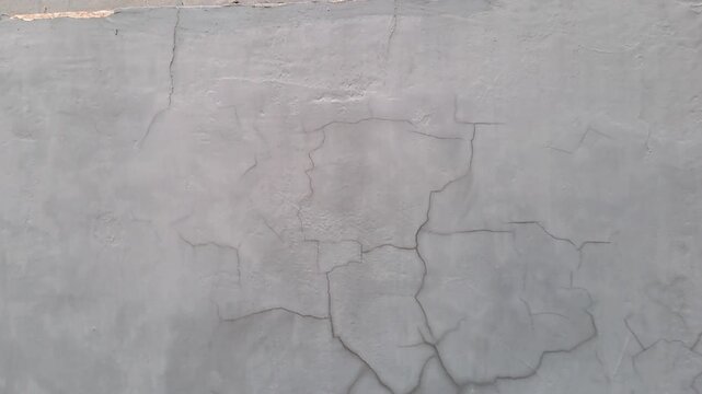 Cracked exterior house wall with mold, grass, and exposed white brick. Damaged plaster texture outdoor. Building deterioration stock video 4K for inspection, construction, repair, maintenance, real es