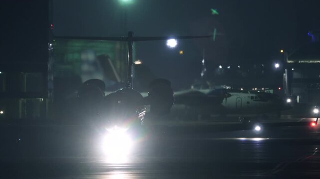 Business Jet Taxiing on Airport Runway at Night &mdash; Static Telephoto Shot | Private Aircraft with Bright Landing Lights on Tarmac | Aviation Night Scene