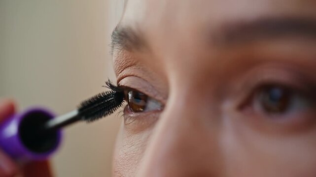 Macro girl applying mascara preparing to day. Closeup woman painting eyelashes