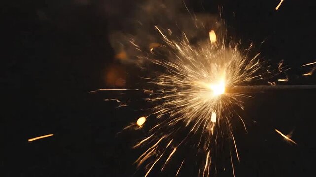 Bright sparkler burning with golden sparks against a dark background