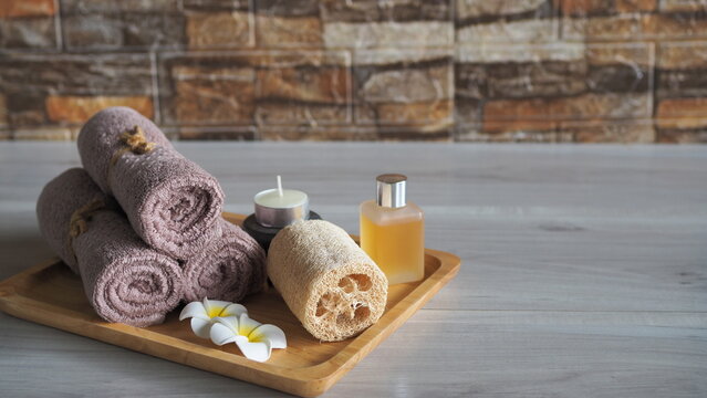 Minimalist flat lay coffee body scrub spa set with organic bath salt in a wooden bowl, a closed amber dropper bottle, cinnamon sticks, and neatly scattered roasted coffee beans. Top view on a warm rus